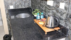 A kitchen counter with a sink, a kettle, a cutting board, and a small potted plant. - DT SUITES  (İstanbul)