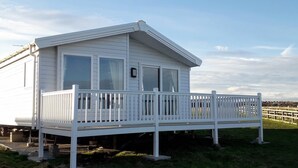 Une maison mobile blanche dotée d’un balcon et de grandes fenêtres.