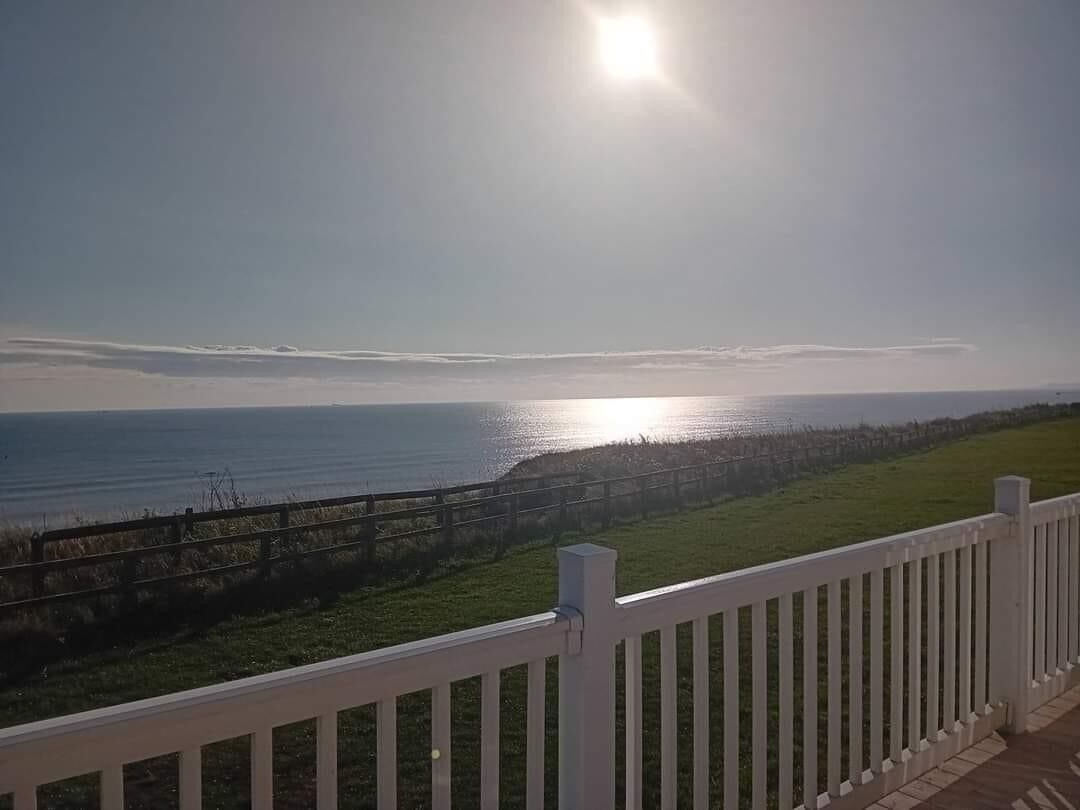 Vista costera con una valla de madera y cielo despejado.