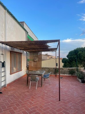 A patio with a table and chairs, a pergola, and a view of the surrounding area. - Stone house in a village (Sant Climent Sescebes)