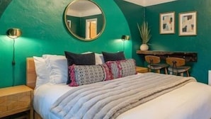 Um quarto com uma cama, um espelho redondo e duas molduras na parede.