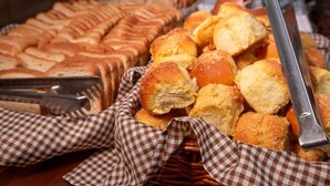 Diverse gebakken producten, zoals brood en gebak, gepresenteerd op een tafel met geruit tafelkleed.