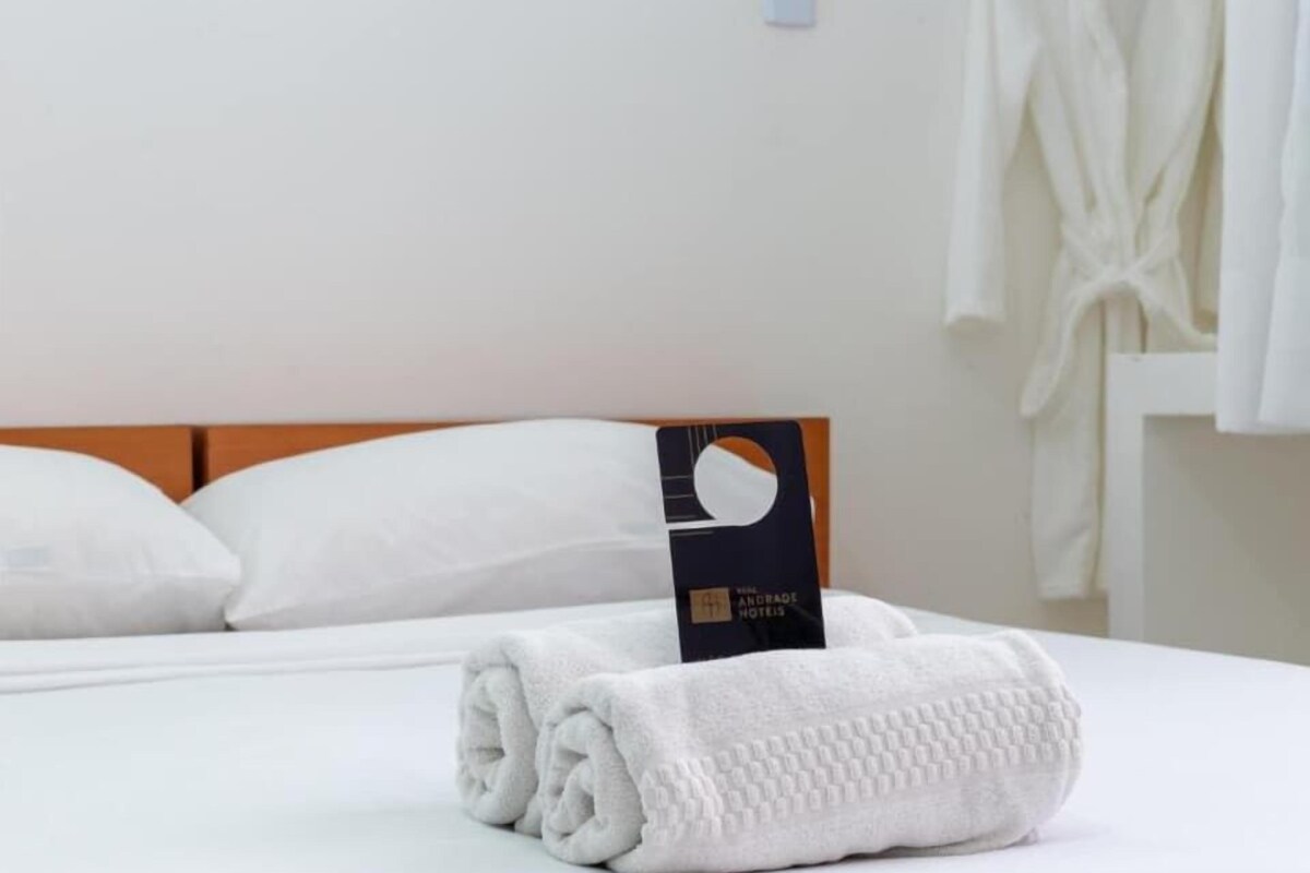 Ein ordentlich bezogenes Bett mit einem gefalteten weißen Handtuch und einer Hotelschlüsselkarte am Kopfteil.