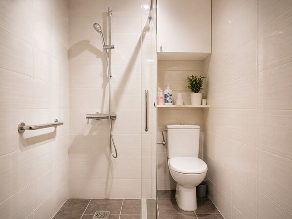 A bathroom with a shower, toilet, and storage shelves. - Heart of Paris – Walk to Louvre, Opera & Vendôme (Paris)
