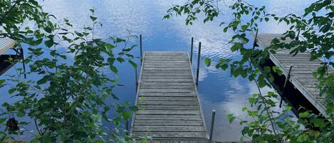 A wooden dock extending into calm water, surrounded by lush green foliage.