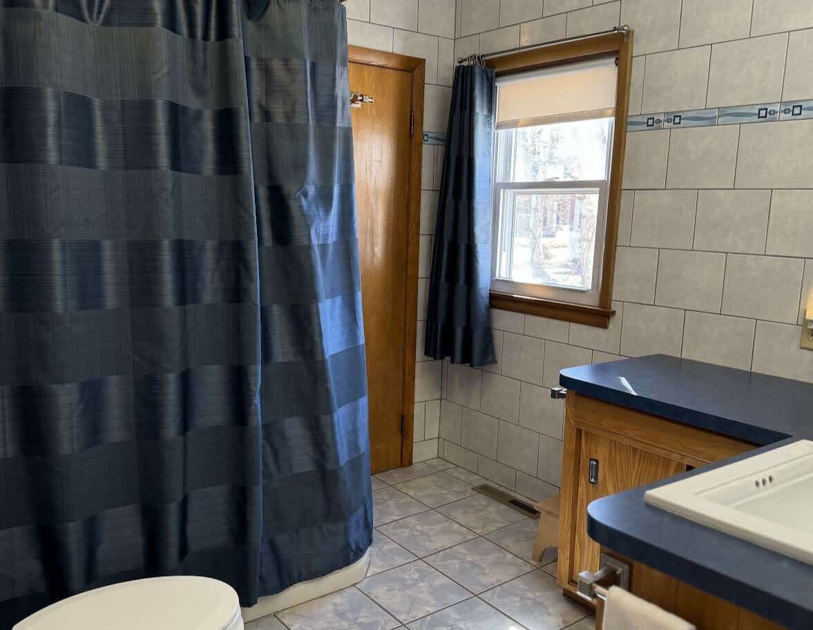 A bathroom with a toilet, sink, and shower curtain.