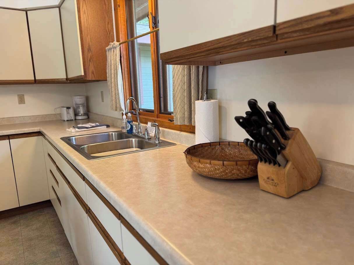 A kitchen with a sink, a wooden knife block, and a woven basket.