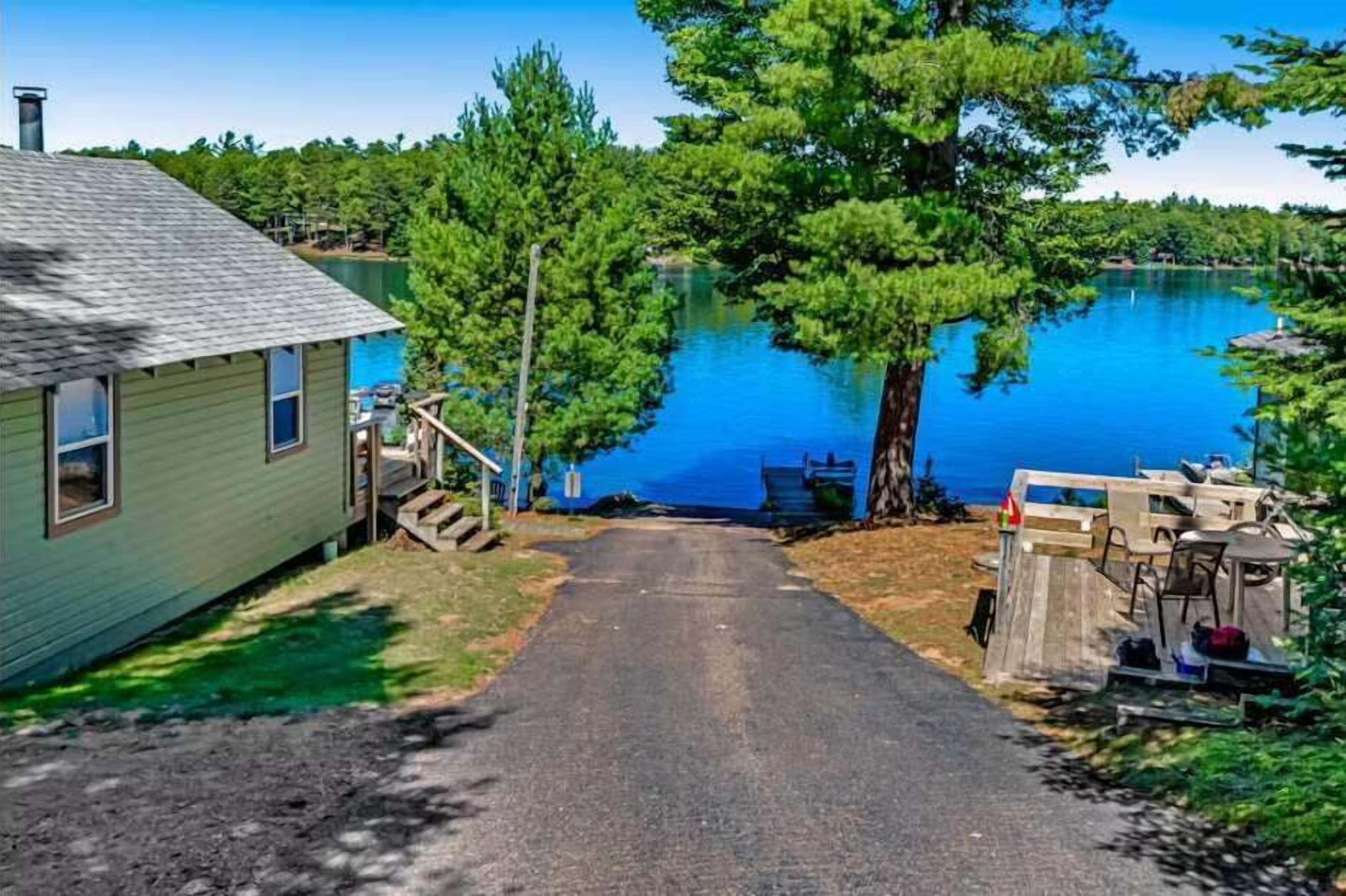 A house with a dock extending into a lake, surrounded by trees.