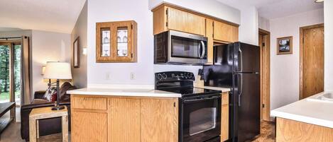 A modern kitchen with wooden cabinets, a black refrigerator, a microwave, and an oven.
