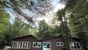 A cabin with a front porch, large windows, and a door. - Moss Lake Lookout: PET Friendly (Lac du Flambeau)