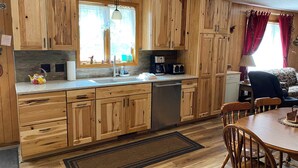 Una cocina con armarios de madera, un fregadero, lavavajillas y un comedor con mesa y sillas.