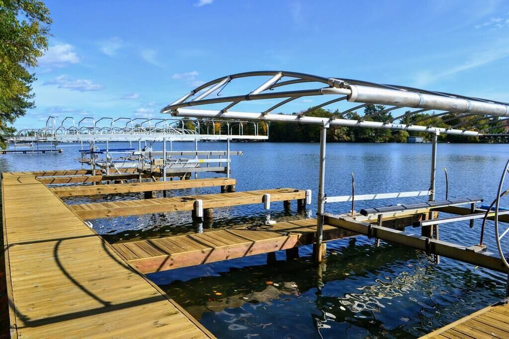 A wooden dock extending into a lake with a metal canopy structure overhead.