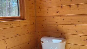 A wooden cabin bathroom with a toilet and a window.