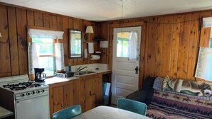 Ein Ferienhaus-Innenraum mit Küchenbereich, einem Esstisch und einer Couch mit Decke.