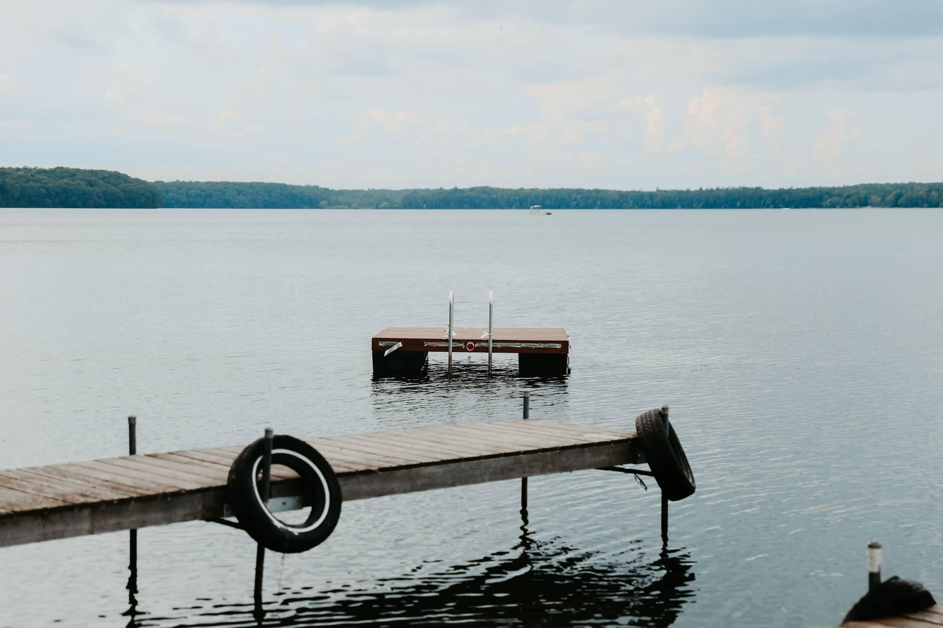 Un muelle de madera que se adentra en aguas tranquilas, con un neumático colgando.