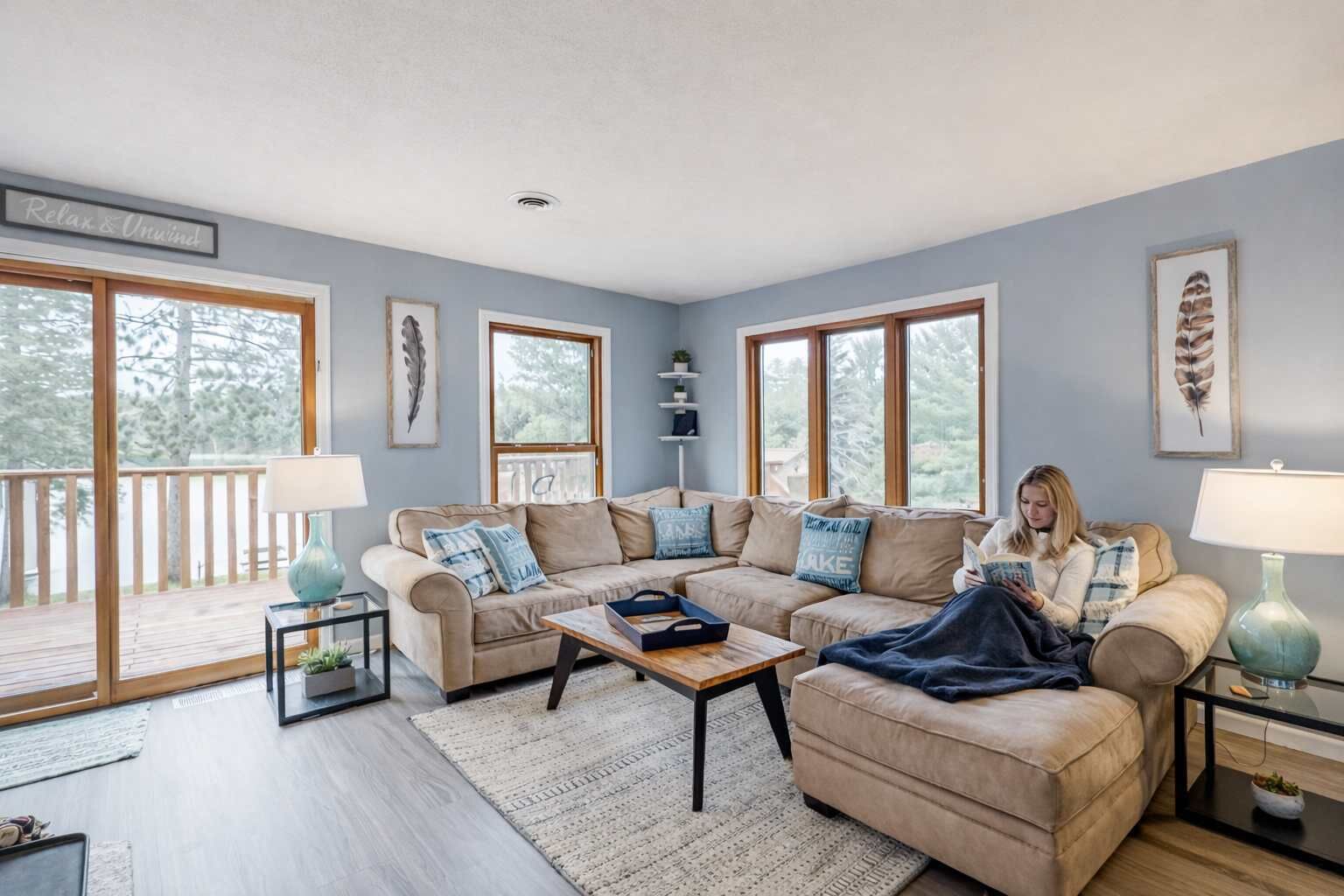 A living room with a sofa, coffee table, and a person reading.