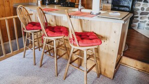 A kitchen with wooden cabinets, a microwave, a stove, and a refrigerator. There are two wooden chairs with red cushions. - Decompression Zone: Direct Access TO Snowmobile Trails (Woodruff)