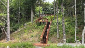 A wooden staircase leading up a hill, surrounded by trees and vegetation. - Decompression Zone: Direct Access TO Snowmobile Trails (Woodruff)