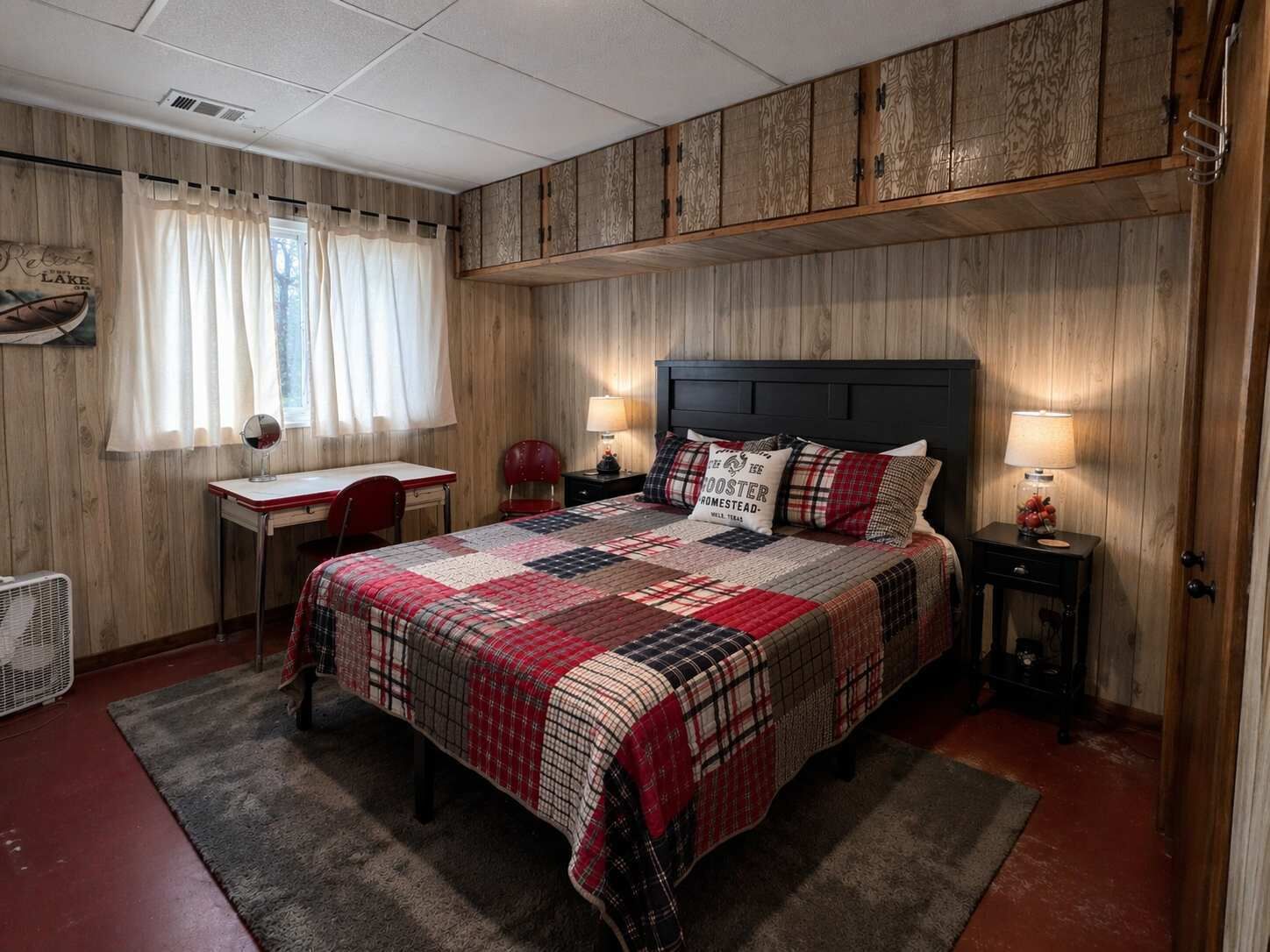 A bedroom with a bed, bedside tables, a desk, a chair, and a window with curtains.