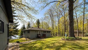 A single-story house with a porch, a lawn, and trees in the background. - Iggy & Al's Treehouse: Northwoods Getaway (Hazelhurst)