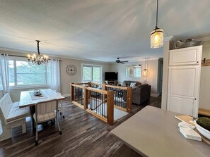 A spacious living area with a dining table, sofa, and a kitchen area with a refrigerator. - Iggy & Al's Treehouse: Northwoods Getaway (Hazelhurst)