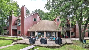 A red building with a covered patio area featuring barbecue grills and outdoor seating. - The Pointe Resort & Club 2 Bedroom Condo (Minocqua)