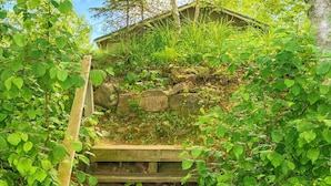 A wooden staircase surrounded by lush greenery, leading to a building with a sloped roof. - Gresham Shores - Hungry Bear - PET Friendly (Woodruff)