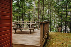 A wooden deck with picnic tables in a forested area. - Old Stoney's Musky - Pet Friendly (Woodruff)