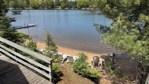 A lakeside deck with outdoor seating and a dock extending into the water. - A Shore Thing: Beach Access (St Germain)