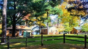 Une cabane rustique avec un espace de stationnement pour remorque à bateau, entourée d’arbres et d’une clôture en bois.