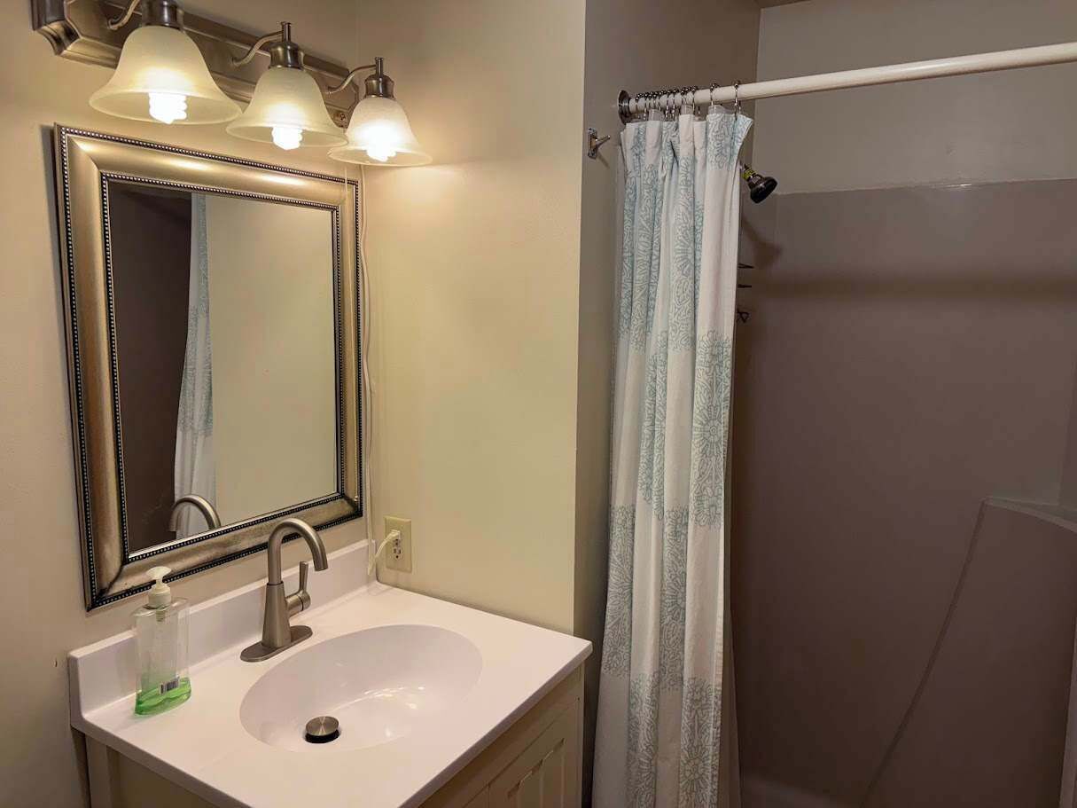 A bathroom with a white sink, a mirror with a decorative frame, and a shower curtain.