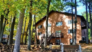 Une cabane avec une façade en bois, de nombreuses fenêtres et un balcon.