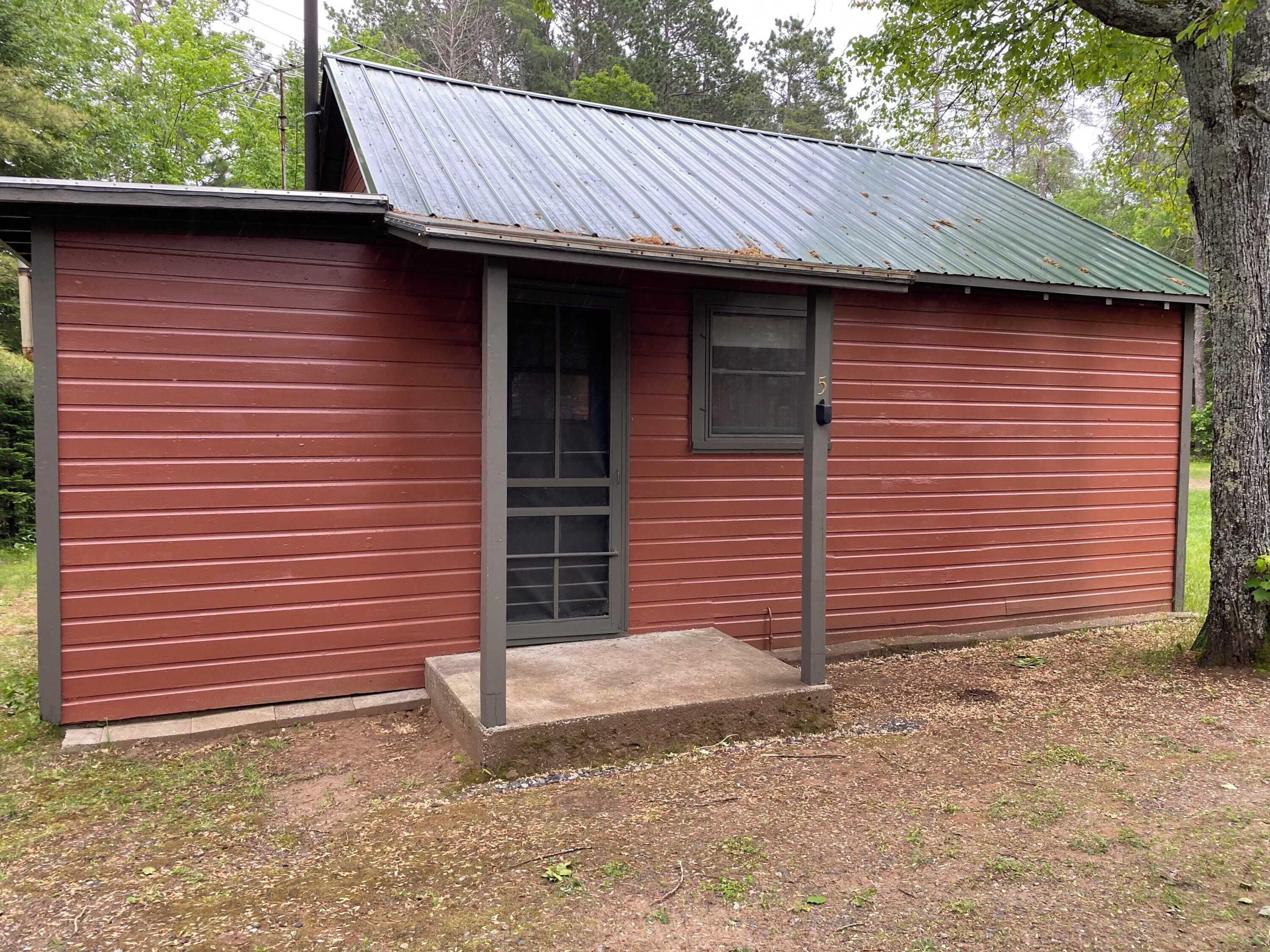 Un petit bâtiment d’un seul étage, doté d’un toit en métal et d’une porte avec une fenêtre.