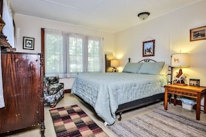 A bedroom with a bed, a chair, a desk, and a lamp. - Hearthwood Beach House - On Lake Tomahawk (Minocqua)