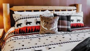 Un lit avec une couvre-lit à motifs, orné d’imprimés d’animaux, et une tête de lit en bois.