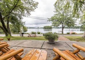 A lakeside patio with wooden benches, a picnic table, and a potted plant. - Island Cove #6 - On Lake Minocqua (Minocqua)