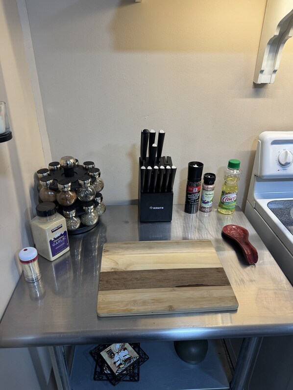 A kitchen counter with various cooking utensils, a cutting board, and containers of spices. - Cozy 1-bedroom apartment in charming Flowery Branch with AC (Flowery Branch)