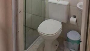 Een compacte, schone badkamer met toilet, douchecabine van glas en een witte wastafel.