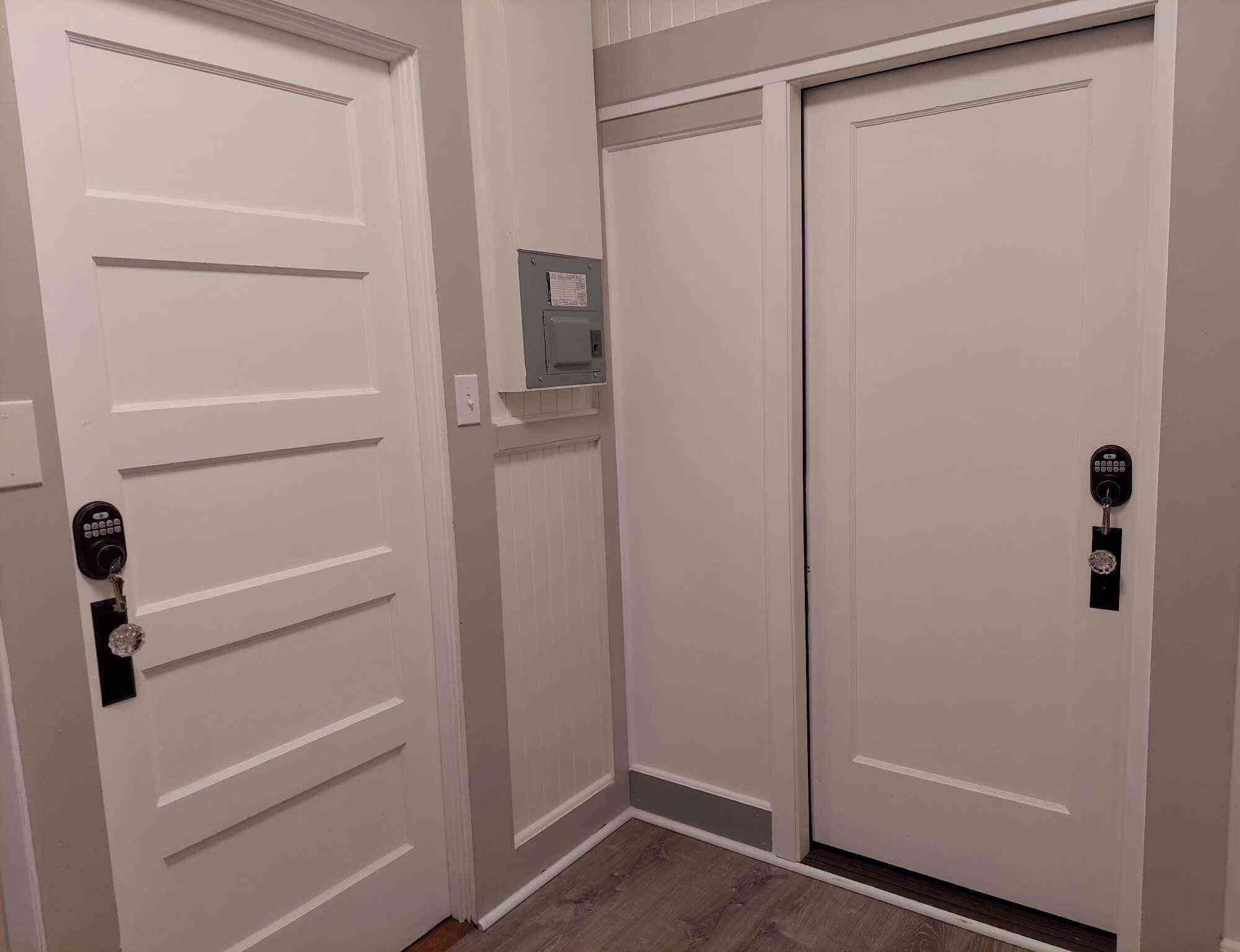 A hallway with two white doors, one with a key lock and the other with a keypad lock.