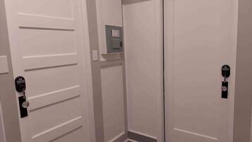 A hallway with two white doors, one with a key lock and the other with a keypad lock.