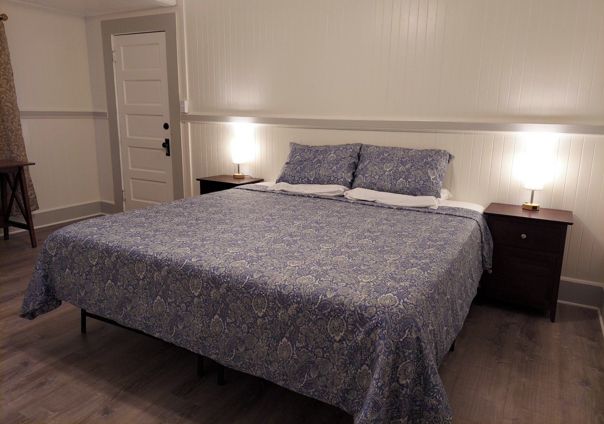 A bedroom with a large bed, two bedside tables, and a door.