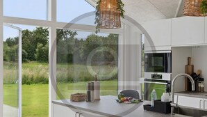 Eine moderne Küche mit großen Fenstern, einem eingebauten Ofen und einer Edelstahlspüle.
