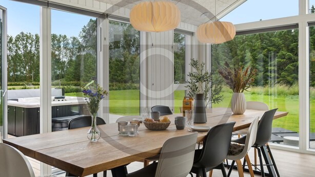 Ein moderner Essbereich mit Holztisch, Stühlen und Blick auf einen üppigen Garten durch große Fenster.