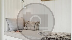 Eine Sitzecke mit Ecksofa, zwei Kissen, einer Zeitschrift und einem Fellüberwurf.