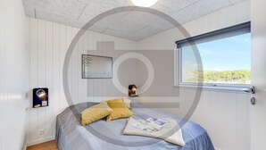 Ein Schlafzimmer mit einem Bett, einem Fenster mit Blick, einer Wandleuchte und einem gerahmten Bild.