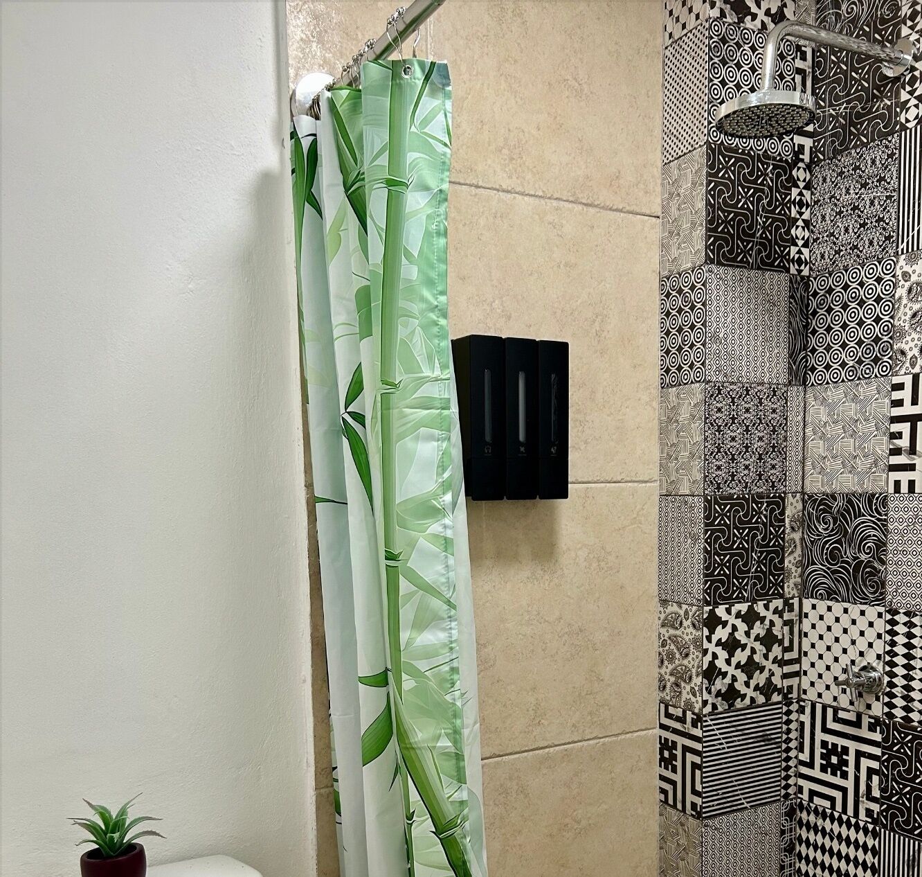 A bathroom with a bamboo shower curtain, a handheld showerhead, and patterned tiles.