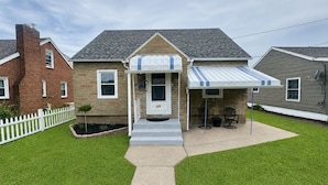 A two-story house with a front porch, a small garden, and a paved driveway. - Super Clean 2BR House: Quiet, Safe, Near Hwy, Big TV, Nightlife, Porch, by River (Beaver)