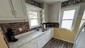 A kitchen with white cabinets, a microwave, a coffee maker, and a sink. - Super Clean 2BR House: Quiet, Safe, Near Hwy, Big TV, Nightlife, Porch, by River (Beaver)