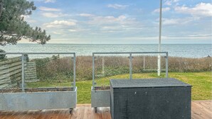 Eine Terrasse mit Meerblick, zwei Pflanzgefäße und ein Metallzaun.
