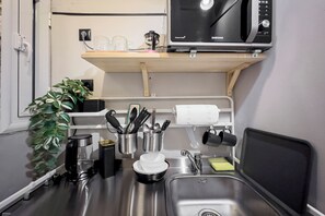 A compact kitchen with a microwave, sink, and various utensils. - Athenian Bliss Spotless Neos Kosmos WiFi Studio (Athina)